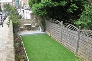 Artificial grass installation with new paving area, timber edging used to create new plant border area.